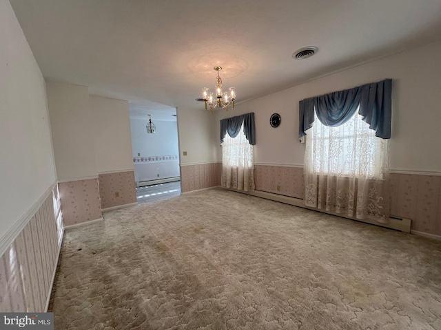 unfurnished room with visible vents, an inviting chandelier, baseboard heating, wainscoting, and wallpapered walls