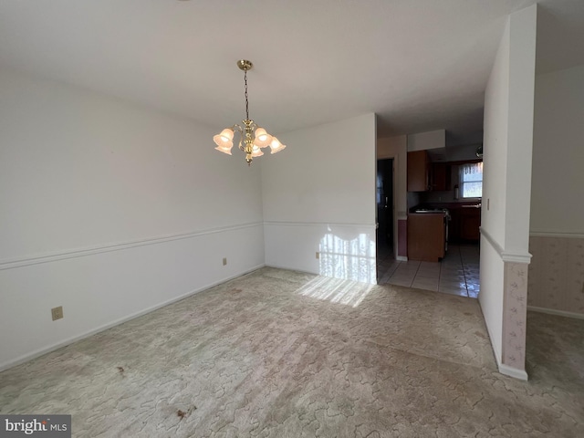 unfurnished dining area featuring baseboards, light colored carpet, and an inviting chandelier