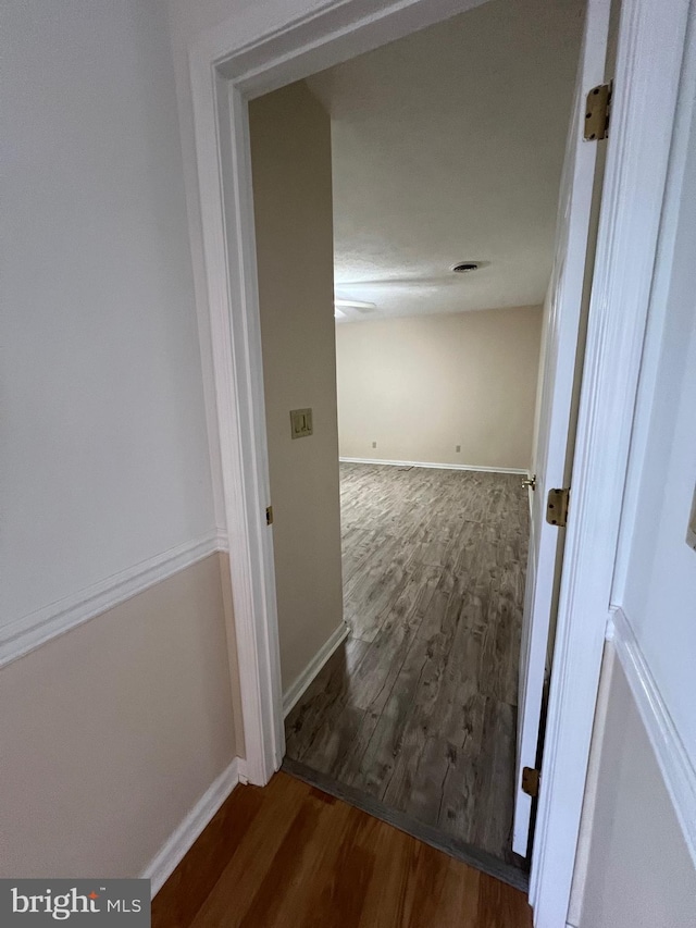 hall featuring visible vents, baseboards, and wood finished floors