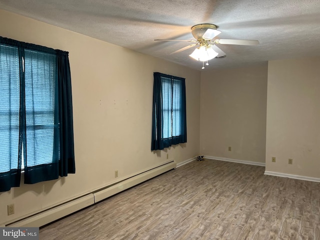 spare room with a baseboard radiator, a healthy amount of sunlight, wood finished floors, and ceiling fan