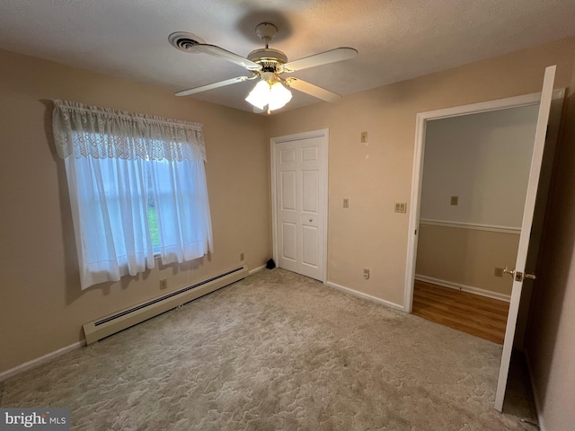 unfurnished bedroom with a baseboard heating unit, baseboards, a ceiling fan, and carpet floors