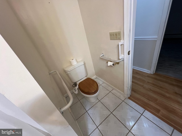 bathroom featuring toilet, tile patterned floors, and baseboards