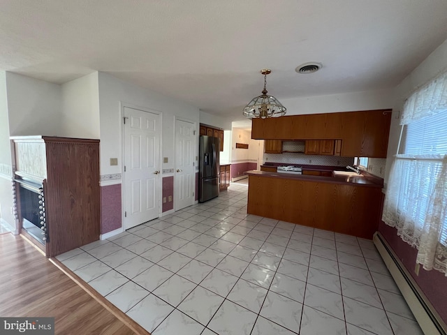 kitchen with a baseboard heating unit, an inviting chandelier, a peninsula, black refrigerator with ice dispenser, and visible vents