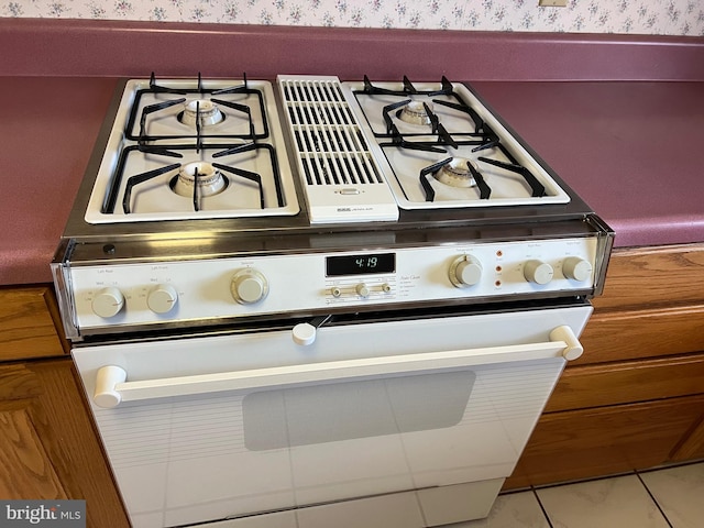 room details with white range with gas stovetop and wallpapered walls