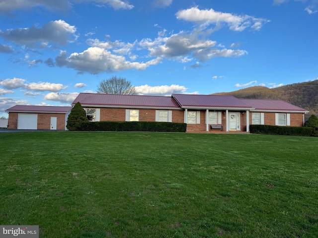 ranch-style home featuring an attached garage, metal roof, a front lawn, and brick siding