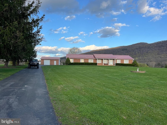 ranch-style home with a front yard, a mountain view, brick siding, and a garage