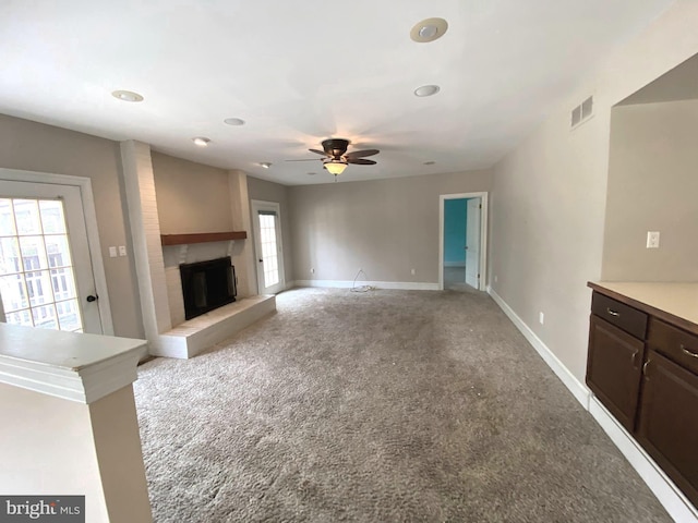 unfurnished living room featuring baseboards, light carpet, visible vents, and a glass covered fireplace