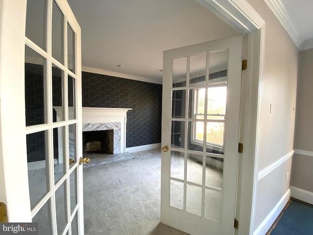 unfurnished living room featuring french doors, ornamental molding, a high end fireplace, and wallpapered walls