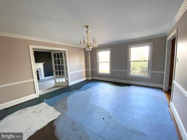 empty room featuring an inviting chandelier, a fireplace, crown molding, and baseboards