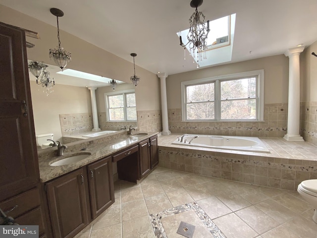 bathroom with a sink, a garden tub, and ornate columns