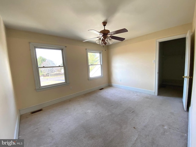 unfurnished bedroom featuring a ceiling fan, light colored carpet, visible vents, and baseboards