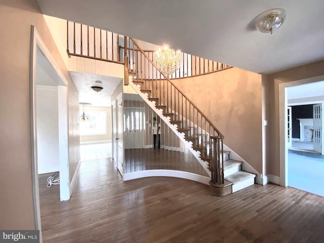 stairway featuring a notable chandelier, baseboards, and hardwood / wood-style flooring