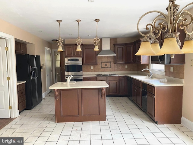 kitchen featuring light countertops, stainless steel double oven, black fridge with ice dispenser, wall chimney exhaust hood, and a sink