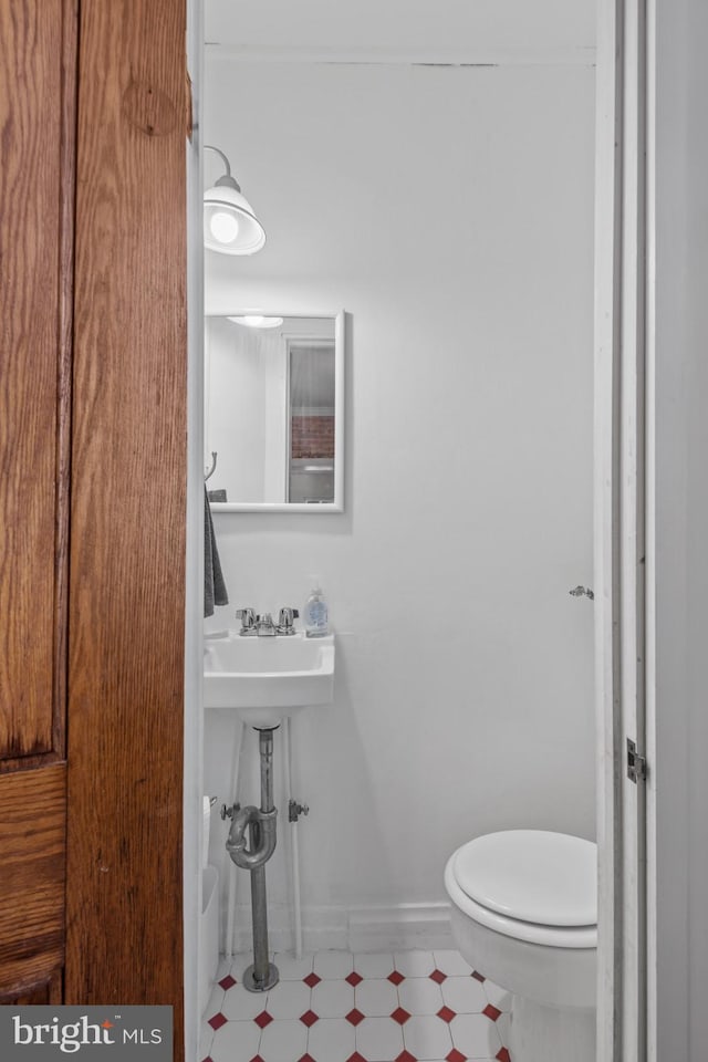 bathroom featuring tile patterned floors, toilet, baseboards, and a sink