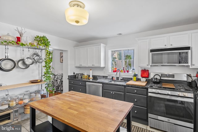 kitchen featuring dark countertops, white cabinets, stainless steel appliances, and a sink