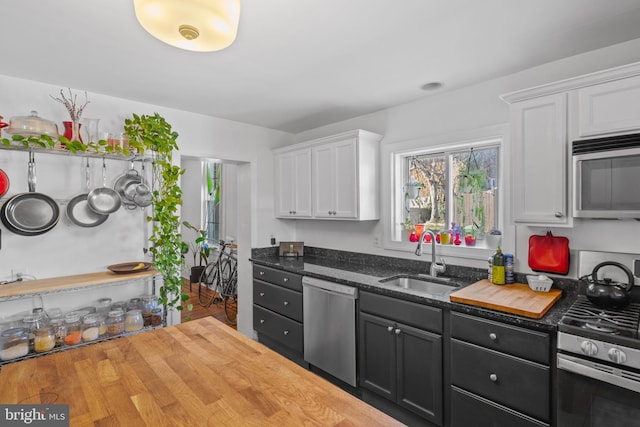 kitchen featuring a sink, wooden counters, appliances with stainless steel finishes, and white cabinetry