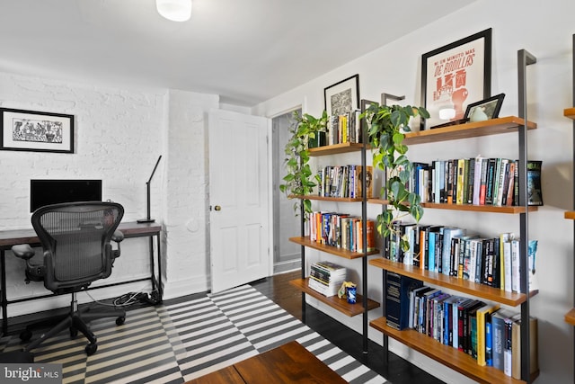 office space with brick wall and wood finished floors