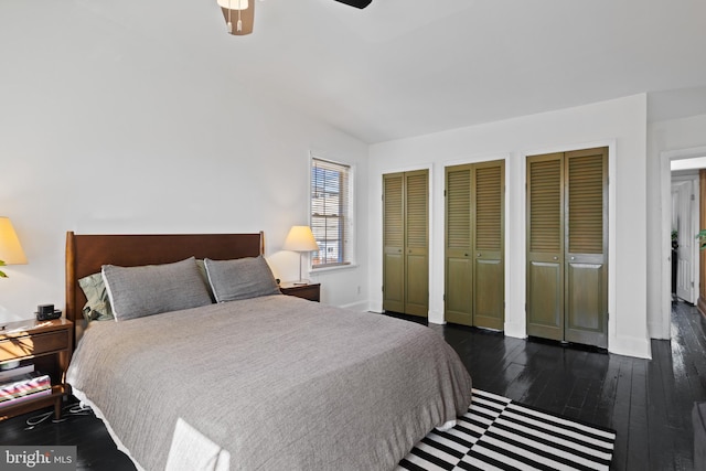 bedroom featuring baseboards, wood-type flooring, two closets, and a ceiling fan