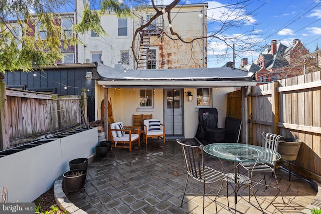 rear view of house featuring a fenced backyard, outdoor dining space, stucco siding, and a patio