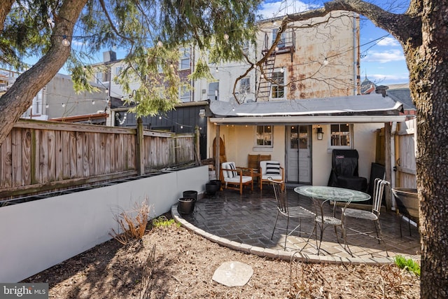 rear view of property featuring stucco siding, a patio, and fence