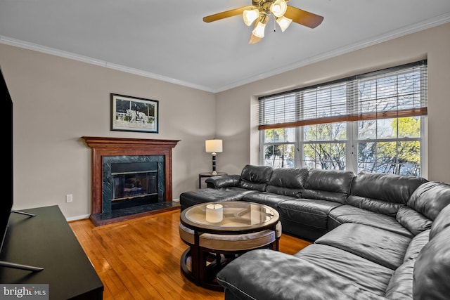 living room with a premium fireplace, a ceiling fan, hardwood / wood-style floors, and crown molding