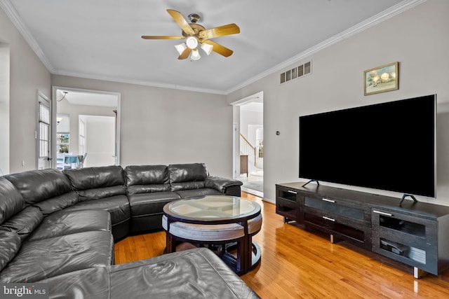 living area featuring crown molding, light wood-style flooring, visible vents, and ceiling fan