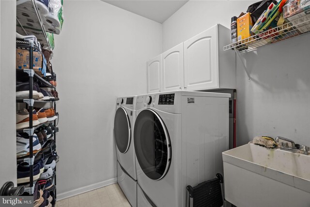 laundry room featuring a sink, baseboards, light floors, cabinet space, and separate washer and dryer