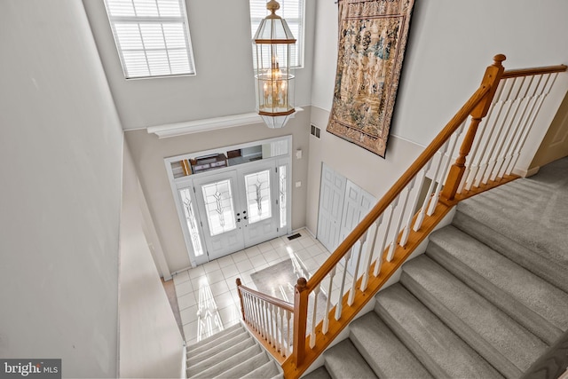 foyer featuring tile patterned floors, a high ceiling, stairway, and visible vents