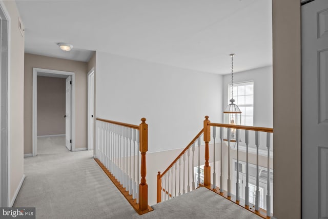 corridor featuring an upstairs landing, baseboards, and carpet floors