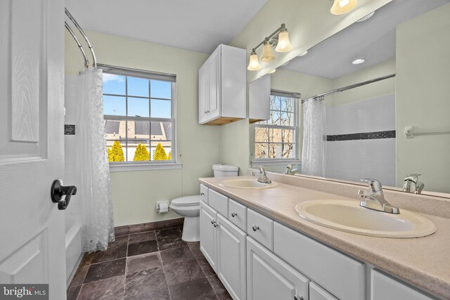 full bathroom featuring double vanity, toilet, stone finish flooring, and a sink