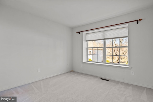 spare room featuring visible vents, baseboards, and light colored carpet