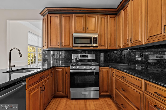 kitchen featuring a sink, brown cabinetry, light wood finished floors, and stainless steel appliances