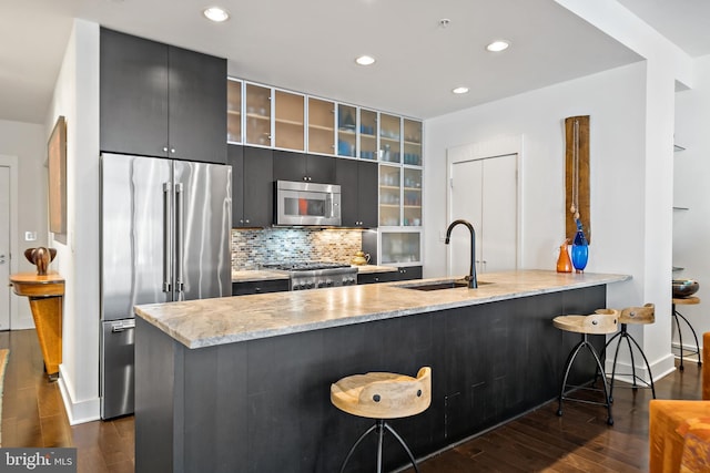 kitchen with a sink, a breakfast bar area, appliances with stainless steel finishes, and dark wood-style floors