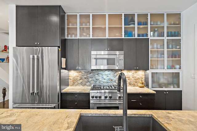 kitchen featuring glass insert cabinets, backsplash, and high end appliances