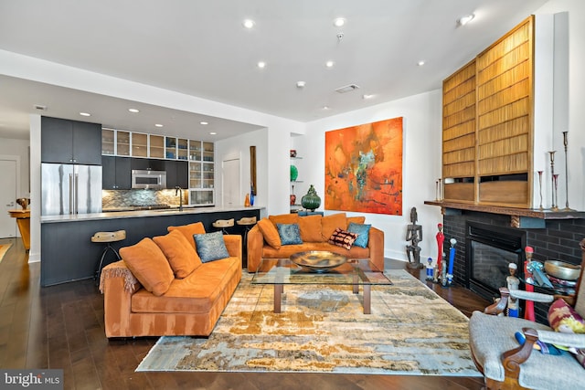 living area with visible vents, recessed lighting, a glass covered fireplace, and dark wood-style flooring