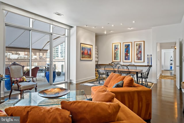 living area with baseboards, wood finished floors, visible vents, and expansive windows