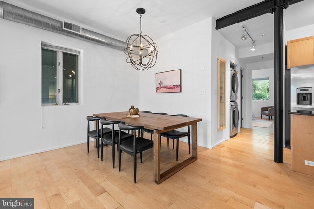 dining space with stacked washer and dryer, track lighting, a chandelier, light wood-style flooring, and visible vents