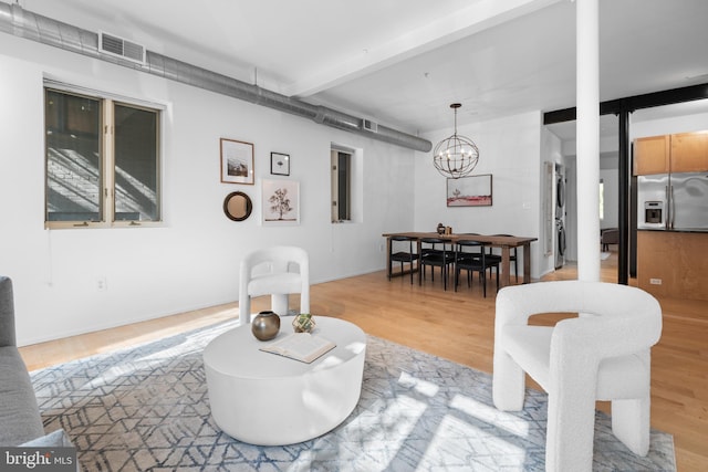 living area featuring a notable chandelier, visible vents, beam ceiling, and light wood-style floors