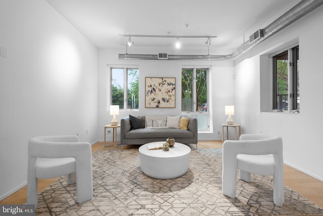 living room with track lighting, baseboards, light wood-style flooring, and visible vents
