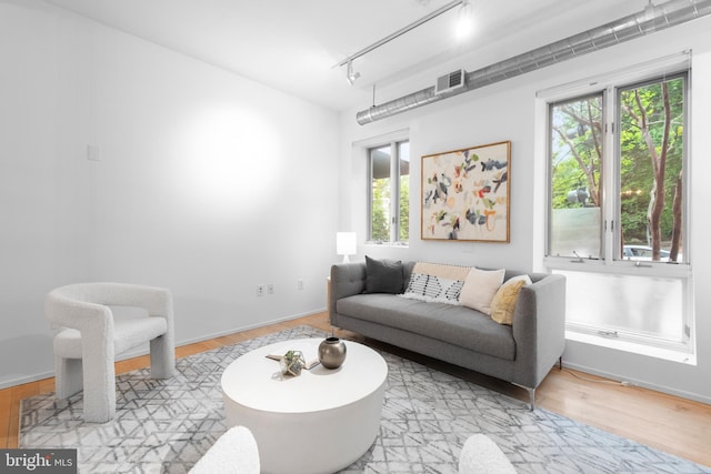 living area featuring rail lighting, visible vents, and wood finished floors