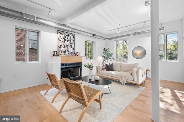 living area featuring visible vents, rail lighting, a fireplace, and hardwood / wood-style floors