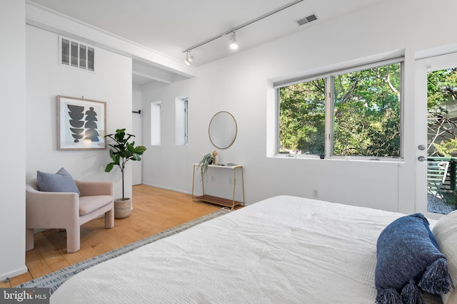 bedroom featuring access to outside, visible vents, track lighting, and wood finished floors