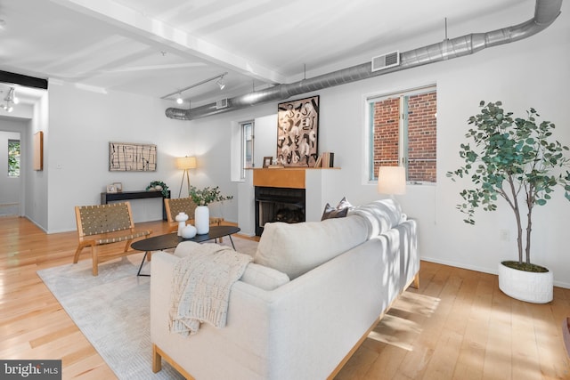 living room featuring visible vents, a fireplace with flush hearth, wood finished floors, and track lighting