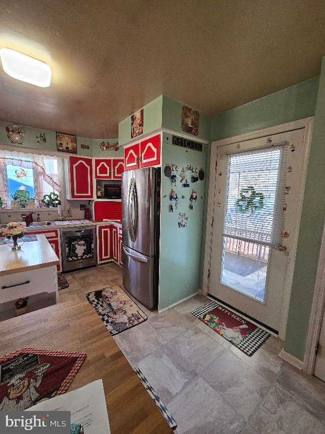 kitchen with light countertops, wine cooler, freestanding refrigerator, and a sink