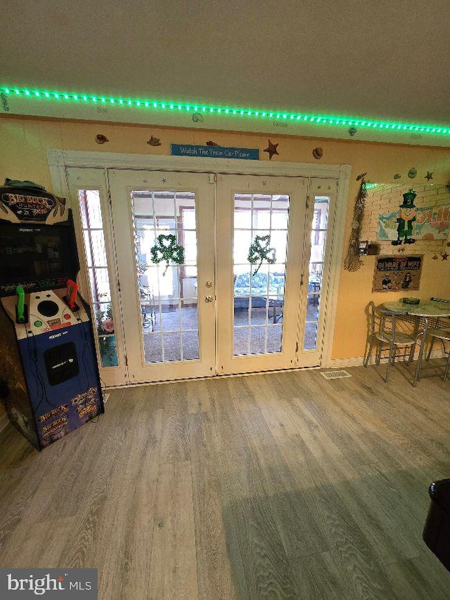 entrance foyer featuring french doors, plenty of natural light, and wood finished floors