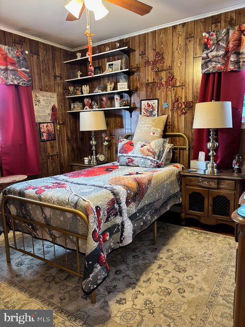 bedroom with wooden walls, ornamental molding, and a ceiling fan