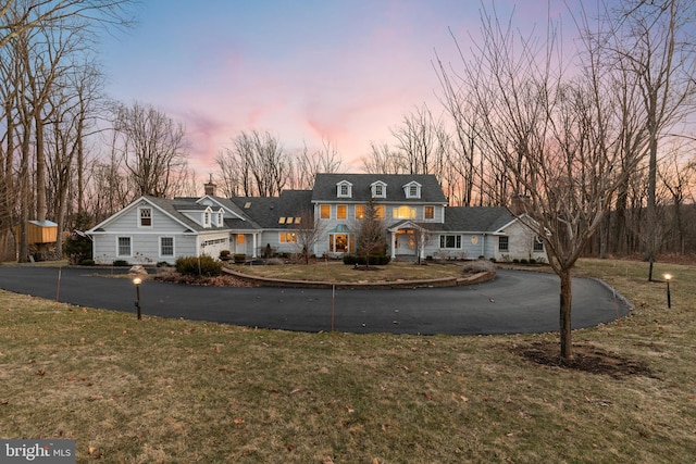 view of front of property with aphalt driveway and a lawn