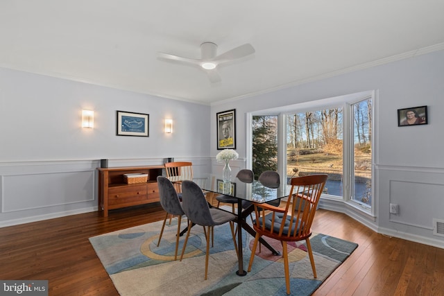 dining area with ornamental molding, visible vents, wood-type flooring, and wainscoting