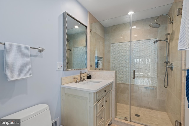 bathroom with vanity, a shower stall, toilet, and visible vents