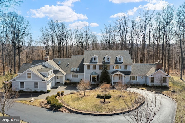 view of front of house with a view of trees and driveway